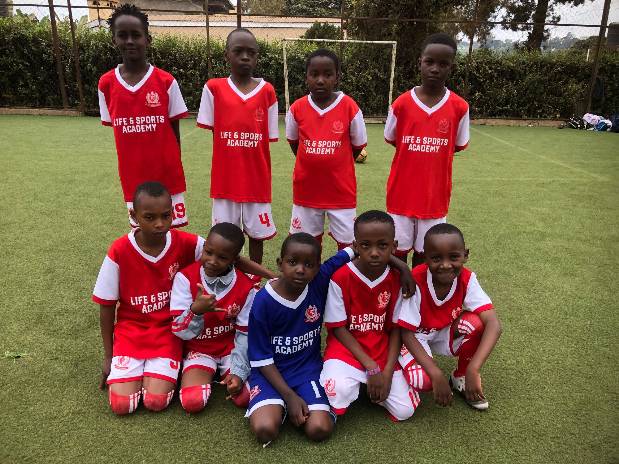 An LSA squad lined up in two rows on the pitch, in red shirts and white shorts